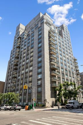 New York apartment for rent - A tall building with many windows is located on a street corner.