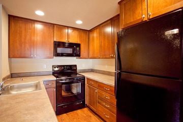 Bend apartment for rent - a kitchen with black appliances and wooden cabinets