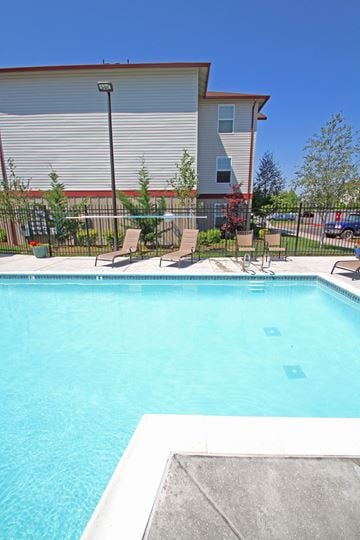 Eugene apartment for rent - a swimming pool with chairs and a building in the background