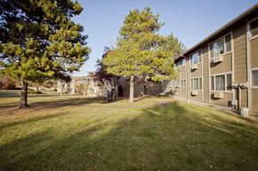 Bend apartment for rent - a view of the exterior of an apartment building with grass and trees
