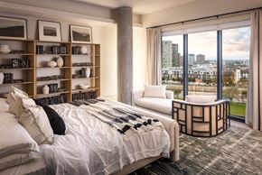 Dallas apartment for rent - A bedroom with a large bed, a chair, and a bookshelf with various books and decorative items.