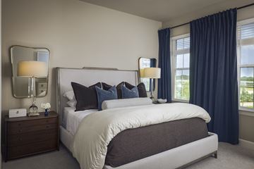 Arlington townhouse for rent - A bedroom with a large bed, a nightstand with a lamp, and a window with blue curtains.
