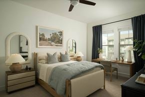 Austin apartment for rent - A bedroom with a large bed, a painting on the wall, and a ceiling fan.