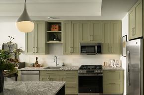 Austin apartment for rent - A kitchen with green cabinets and a stainless steel refrigerator.
