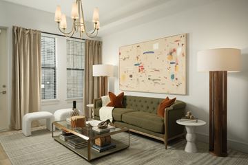 Tempe apartment for rent - A living room with a green couch, a glass coffee table, and a large abstract painting on the wall.
