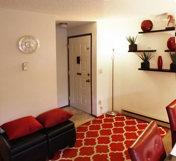 Spokane apartment for rent - A living room with a black couch and red pillows.
