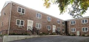 Newark apartment for rent - a red brick building with stairs and a parking lot