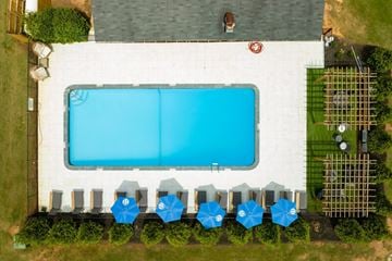 Anderson apartment for rent - A large swimming pool surrounded by blue umbrellas and a white building.