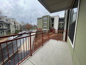 Asheville apartment for rent - A balcony with a red railing overlooks a street with cars and buildings.
