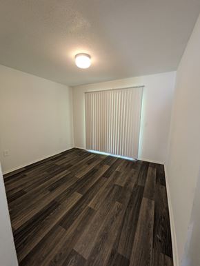 Statesboro apartment for rent - A room with wooden flooring and a window with blinds.