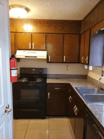 Hinesville apartment for rent - A kitchen with a black oven and brown cabinets.
