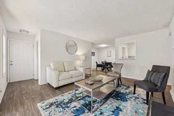 Clarkston apartment for rent - A living room with a white couch, a grey armchair, and a coffee table with a blue rug.