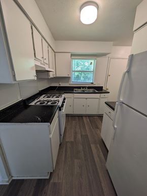 Statesboro apartment for rent - A kitchen with white cabinets and a black countertop.