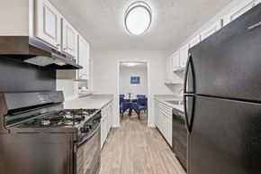 Clarkston apartment for rent - A black refrigerator is in the foreground of a kitchen.
