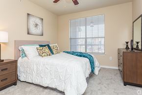 Zachary apartment for rent - A bedroom with a white bed and a ceiling fan.