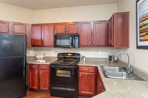 Zachary apartment for rent - A kitchen with brown cabinets and black appliances.