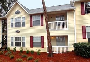 Lawrenceville apartment for rent - A yellow house with red shutters and a tree in front.