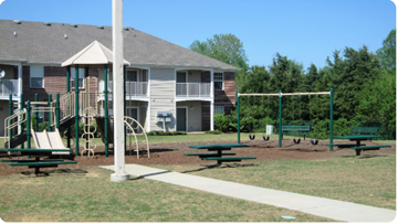 Memphis apartment for rent - A playground with a slide, swings, and picnic tables in front of apartment buildings.