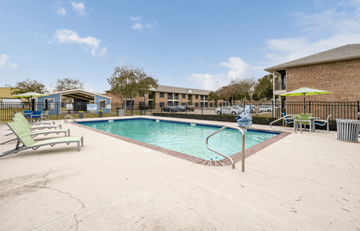 Lafayette apartment for rent - A pool with a sun lounger and umbrella in front of a building.