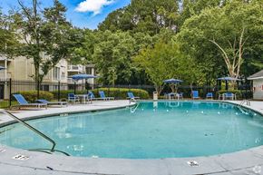Clarkston apartment for rent - A swimming pool surrounded by trees and chairs.