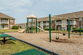 Memphis apartment for rent - A playground with swings and a slide in front of apartment buildings.