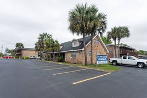 Pensacola apartment for rent - A parking lot in front of a brick building with a sign that says "William Square Apartments" and a phone number.