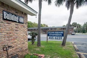 Pensacola apartment for rent - A sign for Lillian Square Apartments is displayed in front of a brick building.