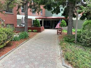 Caribou apartment for rent - a walkway in front of a building with an flag