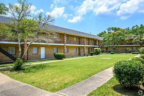 Pensacola apartment for rent - the front of a brick apartment building with a lawn and sidewalk