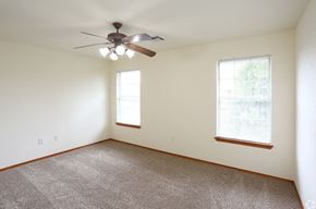 Edmond triplex for rent - a living room with a ceiling fan and two windows