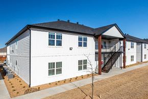 Bentonville apartment for rent - a white building with a gray roof and a brown grassy area in front of it