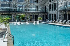 Alexander apartment for rent - a large swimming pool with lounge chairs and a stone building in the background