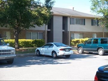 Perry apartment for rent - A white car is parked on the side of the road in front of a building.