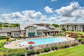 College Station apartment for rent - a swimming pool with lounge chairs and umbrellas in front of a building
