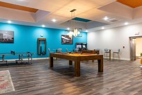 Manchester apartment for rent - a large pool table in a room with a blue accent wall and a game room