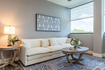 Manchester apartment for rent - A living room with a white couch, a round table with a vase of flowers, and a framed picture on the wall.