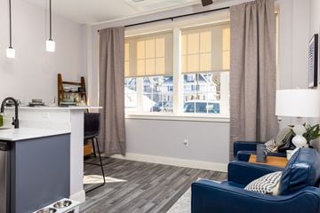 Manchester apartment for rent - A living room with a blue couch and a kitchen area with a sink.