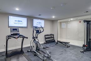 Manchester apartment for rent - a gym with treadmills and weights and a tv on the wall