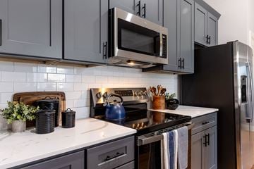 Cranston apartment for rent - A kitchen with a black stove top oven and a black microwave above it.