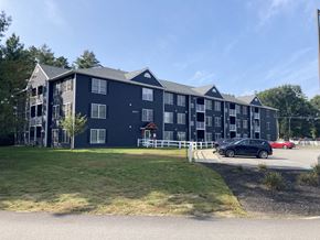 Concord apartment for rent - A large building with a dark blue exterior and a white fence in front.