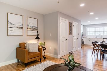Laconia apartment for rent - A living room with a brown chair and two landscape paintings on the wall.