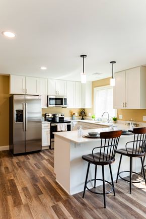 Laconia apartment for rent - a kitchen with white cabinets and a island with three chairs