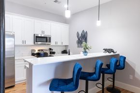 Manchester apartment for rent - A kitchen with white cabinets and a white island with blue chairs.