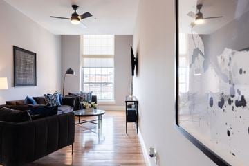 Manchester apartment for rent - A living room with a black couch and a large abstract painting on the wall.