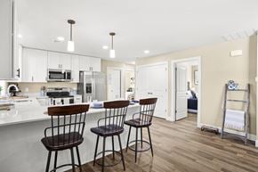 Lebanon apartment for rent - a kitchen with white cabinets and a bar with three stools