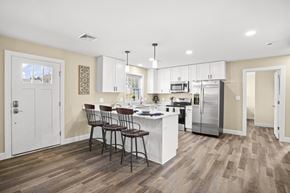 Lebanon apartment for rent - a kitchen with white cabinets and a white island with three chairs