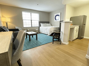 Charlotte apartment for rent - A bedroom with a bed, chair, and a small table.