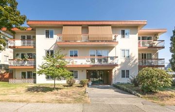 Vancouver apartment for rent - A large white apartment building with balconies and a driveway in front.