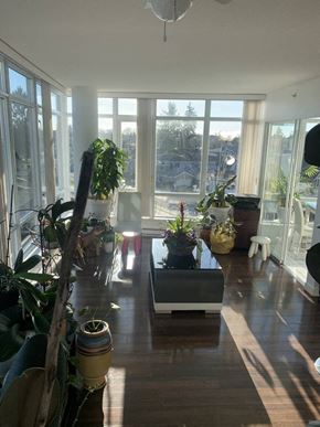 Vancouver condo for rent - A sunny day in a living room with a large window and a wooden floor.