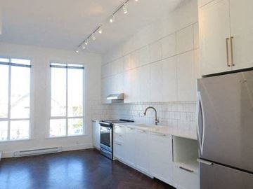Surrey townhouse for rent - A kitchen with white cabinets and a black fridge.